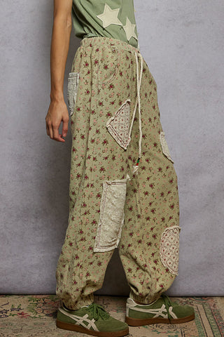 Sage green jogger pants with a floral patchwork design and elastic waistband