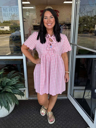 Pink gingham dress with scalloped trim, featuring a bow front design for a charming, vintage-inspired look. Perfect for summer.