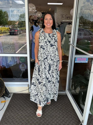 Navy tropical print halter neck maxi dress displayed on mannequin, showcasing elegant flow and vibrant floral pattern.