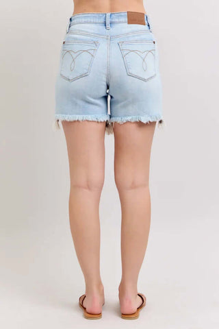 Close-up of Judy Blue light wash cut-off denim shorts with two-button detail, frayed hem, and classic five-pocket design.