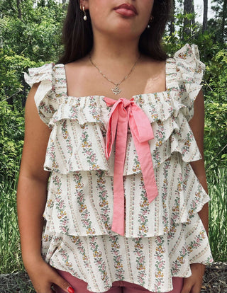 Ivory and pink floral Bibi Top featuring a square neck, bow, and ruffles for a chic, feminine look. Perfect for any occasion.