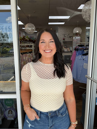 Cream round neck dot lace mesh short sleeve layering top on hanger, showcasing intricate lace design and elegant style.