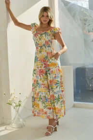 Woman in a flowy Beach Day Vacay Maxi Dress with vibrant tropical print enjoying a sunny day in the sand. Final Sale item.