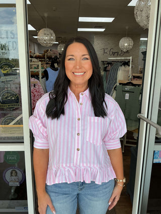 Pink Stripe Oxford Ruffled Hem Button Up Top on hanger, showcasing elegant design and vibrant stripes in natural light.