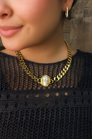 Close-up of a person wearing a gold chain necklace with a pendant.