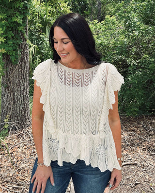 &Merci Off White Crochet Flutter Sleeve Sweater Top displayed on a hanger against a textured gray background.