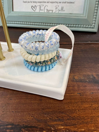 Close-up of Simply Southern Flower Blue Coil Hair Ties, featuring blue floral patterns, neatly coiled for stylish and secure hair styling.