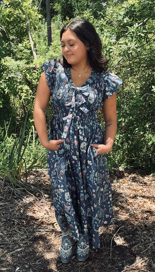 Alt text: "Elegant midnight blue floral midi dress with cap sleeves and bow accent by Entro.