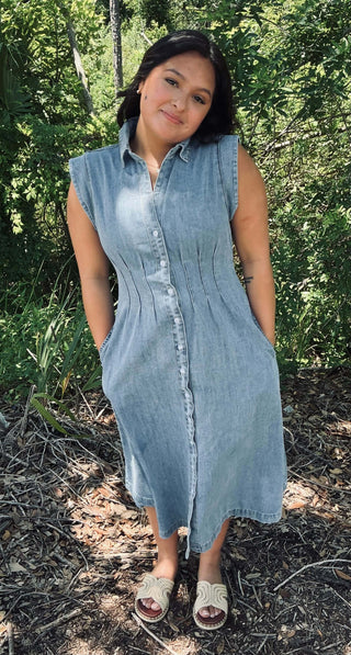 Washed light denim shirt dress with collar, pintuck‑cinched waist and button‑front closure—short sleeves and relaxed midi length