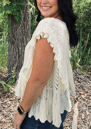 &Merci Off White Crochet Flutter Sleeve Sweater Top on a hanger against a beige background, showcasing intricate crochet details.