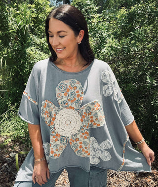 Alt text: "Blue velvet orange ivory lace flower patchwork oversized top displayed on hanger with intricate design details.
