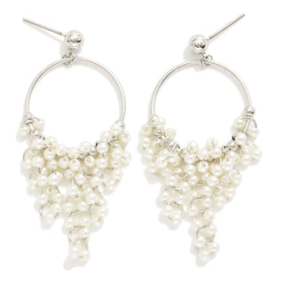 Alt text: "Elegant silver and pearl tassel post drop hoop earrings, stylish and modern jewelry piece displayed on a soft beige surface.