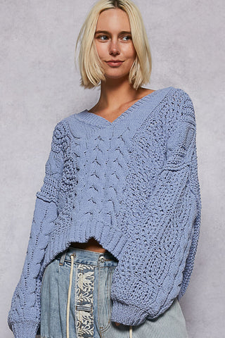 Oversized cable knit v-neck sweater in soft cream, featuring a relaxed fit and textured fabric.