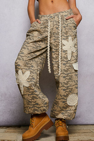 Beige camo patchwork joggers featuring ivory crochet patches and a relaxed fit