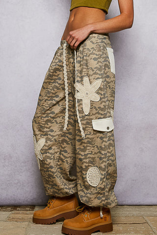 Beige camo patchwork joggers featuring ivory crochet patches for a stylish, casual look