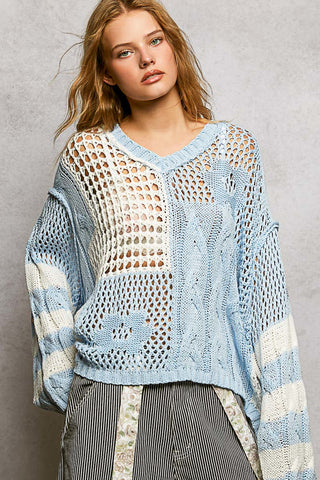 Light blue and cream color block open weave sweater with long sleeves and V-neckline.
