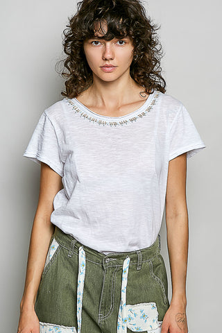 White short-sleeve tee with beaded neckline detail and textured fabric.

