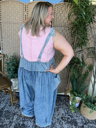 Pink and blue denim oversized jumpsuit with chest pockets and adjustable straps on model.

