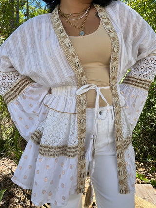 Ivory shell kimono with textured striping, shell embellishments, and taupe trim details worn open over cream top.
