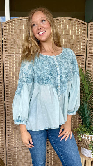 Light blue embroidered peasant top with three-quarter puffed sleeves and button front placket.
