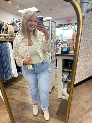 Ivory textured floral blazer with button front and ruched sleeves over cream camisole and light blue jeans.

