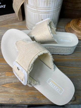 Beige linen flatform slide sandals with frayed textile strap and white rubber sole.
