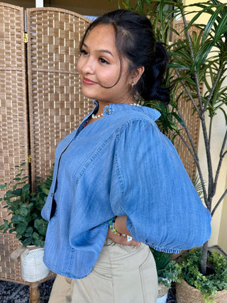 Blue chambray button-up shirt with puffed sleeves and relaxed fit styling.
