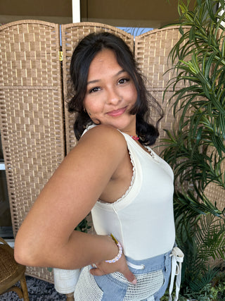 White ribbed knit tank top with lace trim neckline on model.
