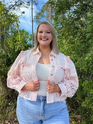 Blush pink lace shacket with button front and ruffled sleeves over white tank top.
