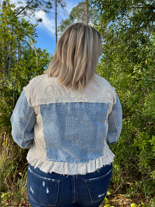 Blue denim jacket with cream lace collar and eyelet embroidery yoke detail.
