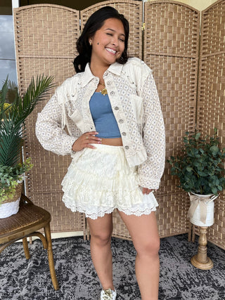 Ivory textured button-up jacket with floral quilting detail paired with white lace skirt.
