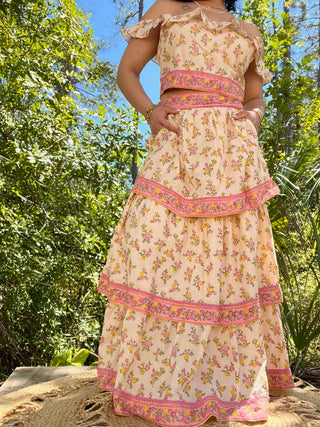 Cream floral crop top and maxi skirt set with pink embroidered trim and yellow, pink floral print.
