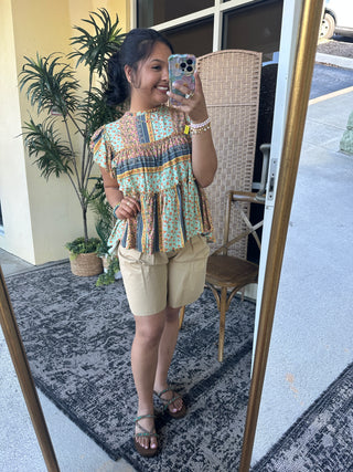 Turquoise and rust floral print peplum top with navy stripe detail and short ruffle sleeves.
