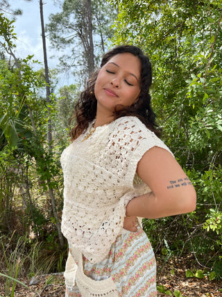 Cream crochet short-sleeve top with intricate openwork pattern and textured knit design.
