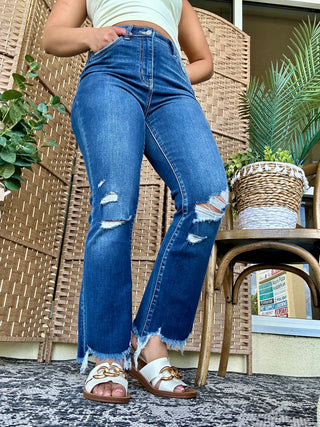 Dark wash high-rise crop flare jeans with distressed knee rips and raw frayed hem.
