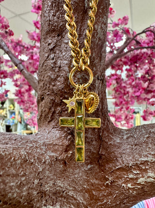 Gold chain necklace with ornate cross pendant featuring sage green stone inlays and charm detail.
