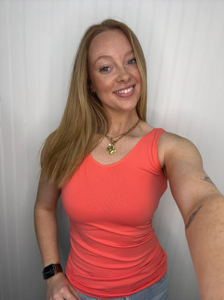 Hot coral seamless tank top with ruched sides on model, paired with necklace and smart watch.
