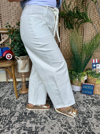 White gypsy fit pants with embroidered floral details and rope belt tie.
