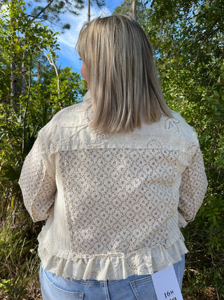 Ivory lace jacket with floral embroidery, puffed sleeves, and ruffled hem detail.
