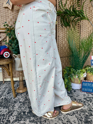 Ivory gypsy fit pants with red polka dot pattern, full length view on model.

