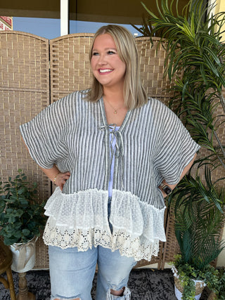 Black and white striped kimono top with white eyelet ruffled hem and tie-front closure.
