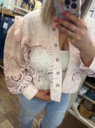 Blush pink lace shacket with intricate floral cutout details and button front closure.

