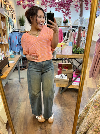 Coral crochet short-sleeve top with textured knit pattern paired with denim jeans.
