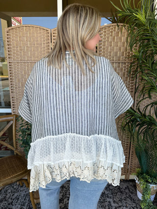 Black and white striped kimono with white ruffled lace hem, worn over light blue jeans.
