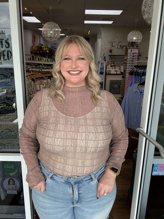 Easel Mocha Plaid Mesh Layering Top displayed on a hanger against a white wall, showcasing its stylish mesh design and cozy plaid pattern.