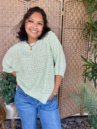 Mint green asymmetrical sweater with textured knit and three-quarter puffed sleeves.
