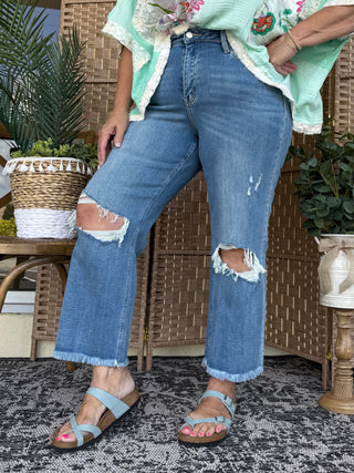 Medium blue distressed wide leg crop jeans with ripped knees and frayed hem.
