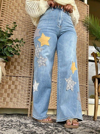 Blue wash denim pants with gold and silver star patches and patchwork details throughout.
