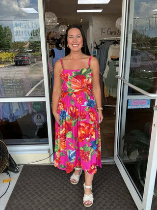 Woman wearing a Magenta Braided Strap Floral Print Midi Dress by Skies Are Blue, standing in a garden setting.