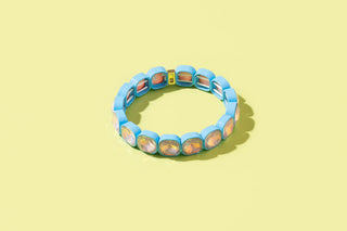 Blue beaded stretch bracelet with iridescent orange and amber square stone accents.
